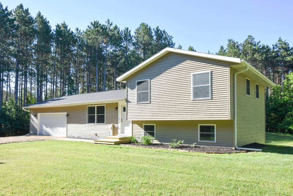 Contemporary house with large yard and forest background in Wisconsin.