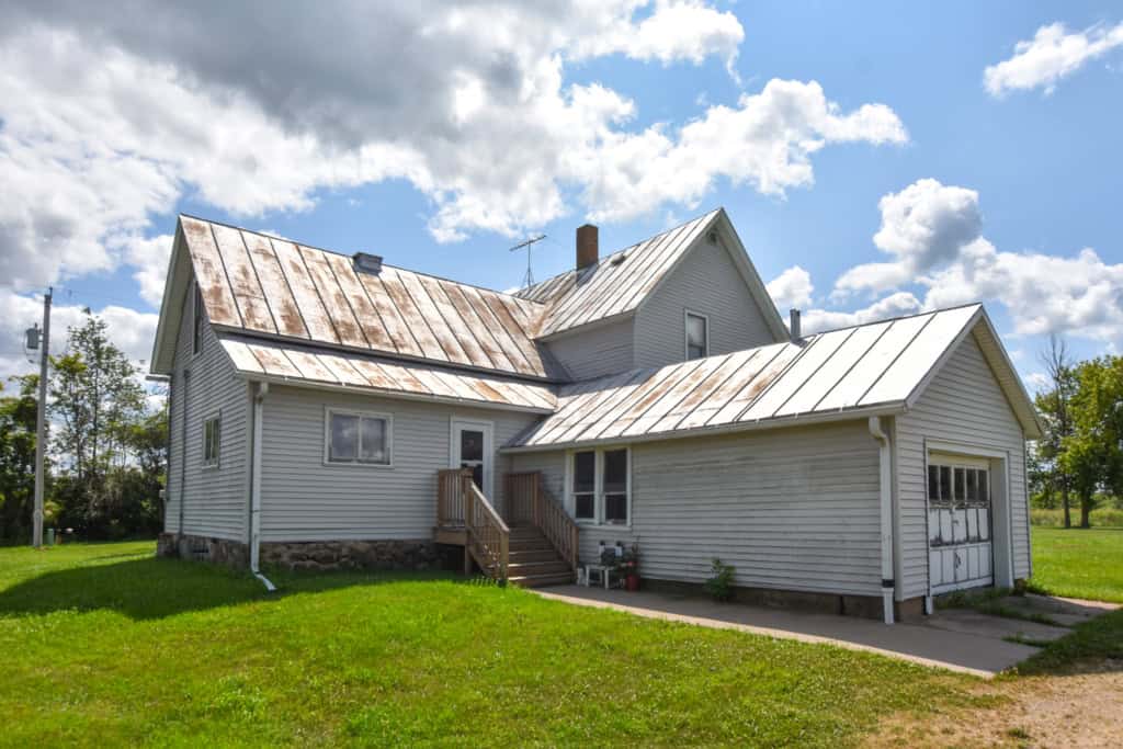 White country house with metal roof in Wisconsin countryside.
